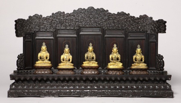 At the Met: Treasures from the private Forbidden City retreat of an 18th century Chinese monarch. In this image, a row of statues of Amitabha on a purple sandalwood stand.